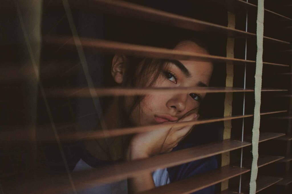 Woman with summer depression looking out a window